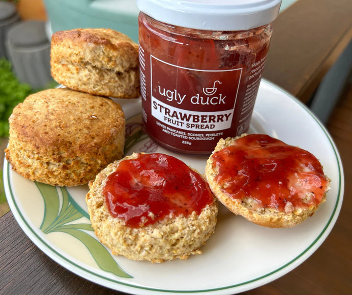 Freshly baked homemade scones on a plate with fresh strawberry jam made from seconds strawberries. The scones were made from freshly milled organic soft wheat grain. The soft wheat grain was a variety called purple straw. Purple straw is a soft wheat grain that is perfect for cakes, biscuits, cookies and scones