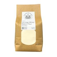 A 1kg bag of Sovereign Foods Heritage Wheat Bakers Flour in a brown kraft paper bag with a white label and a clear window showing the pale flour inside.